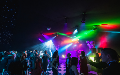 Guests dancing beneath vibrant stage lighting at an Ultimate Wonder Nights shared Christmas party in London