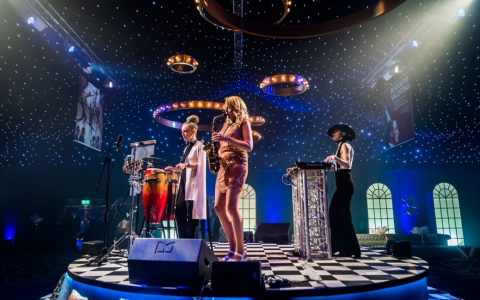 Live band with saxophonist, percussionist and DJ performing under a starlit ceiling at an Ultimate shared Christmas party in London